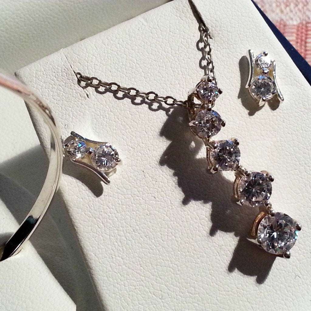 Conjunto con incrustaciones de brazalete, aretes, cadena y colgante de plata de ley con circonitas cúbicas.