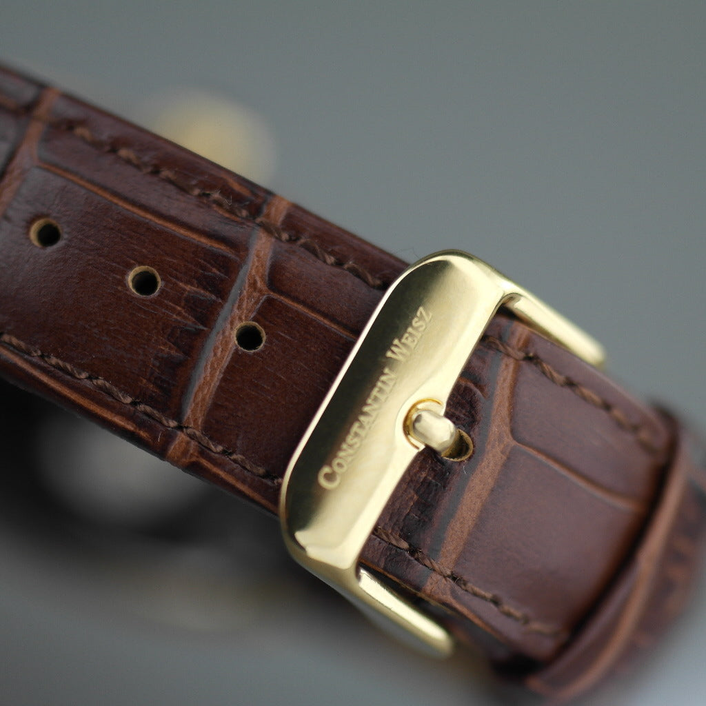 Reloj mecánico Constantin Weisz chapado en oro con correa de piel marrón.
