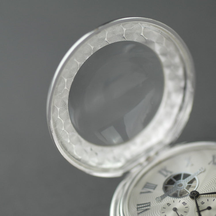 Reloj de bolsillo bañado en plata con números romanos e indicador de día y noche.