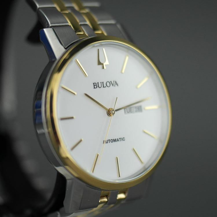 Reloj automático Bulova para hombre con esfera blanca y fecha bilingüe con pulsera de acero inoxidable y elementos chapados en oro