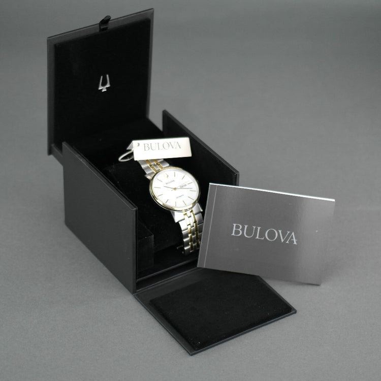 Reloj automático Bulova para hombre con esfera blanca y fecha bilingüe con pulsera de acero inoxidable y elementos chapados en oro